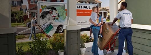 A couple of people standing next to a uhaul truck.